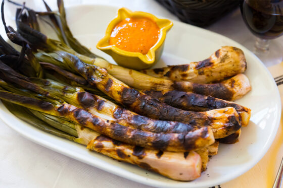 A plate of Calçots, traditional Catalan dish served in a restaurant in Tossa del Mar
