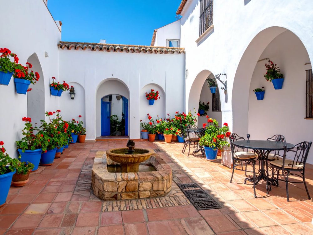 Traditional courtyard full of flower pots at a simple hotel near the Mezquita. AI-generated image.
