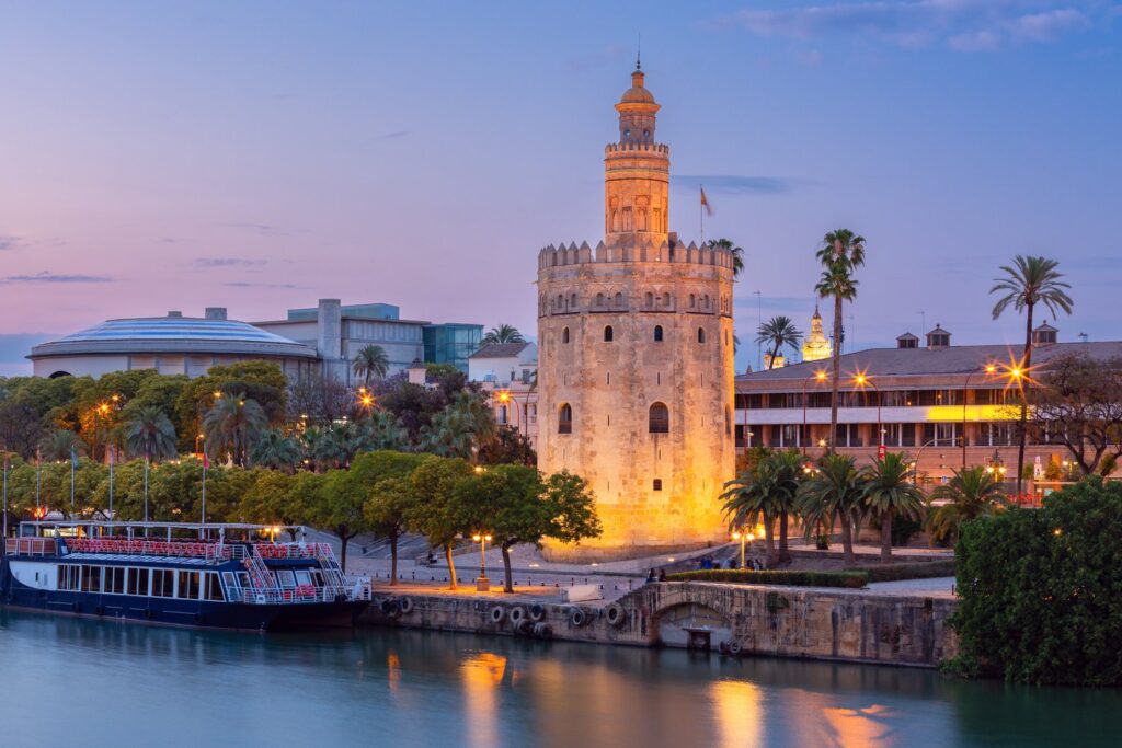 The Torre del Oro watchtower glows at sunset on the banks of the Guadalquivir